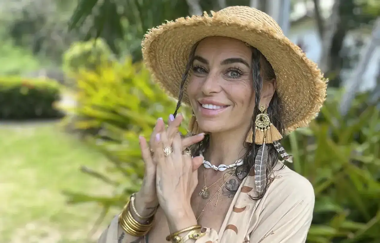 Kasia nastraja pozytywnie w słomkowym kapeluszu i boho biżuterii, uśmiecha się na tle zieleni.