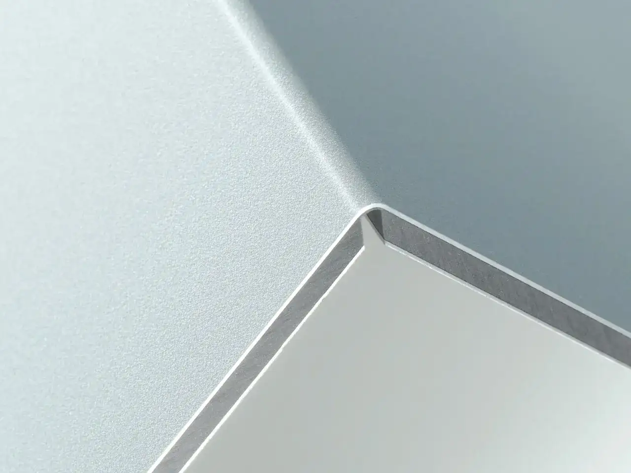 Szara, matowa powierzchnia z połyskującą krawędzią, przypominająca nowoczesny panel alucobond.