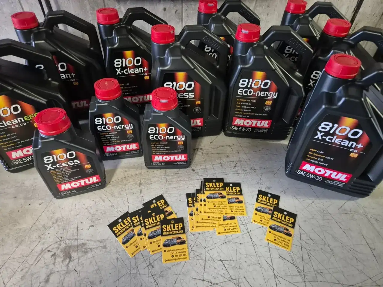Butelki oleju silnikowego Motul 8100 X-cess i X-clean, karty z logo sklepu.