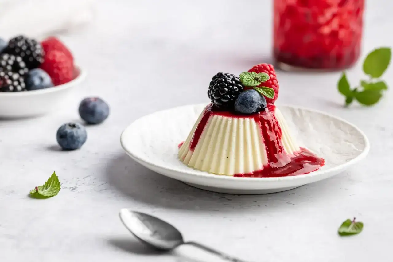 Vegane Panna Cotta mit Beerensoße und frischen Beeren, ein leichter Genuss.