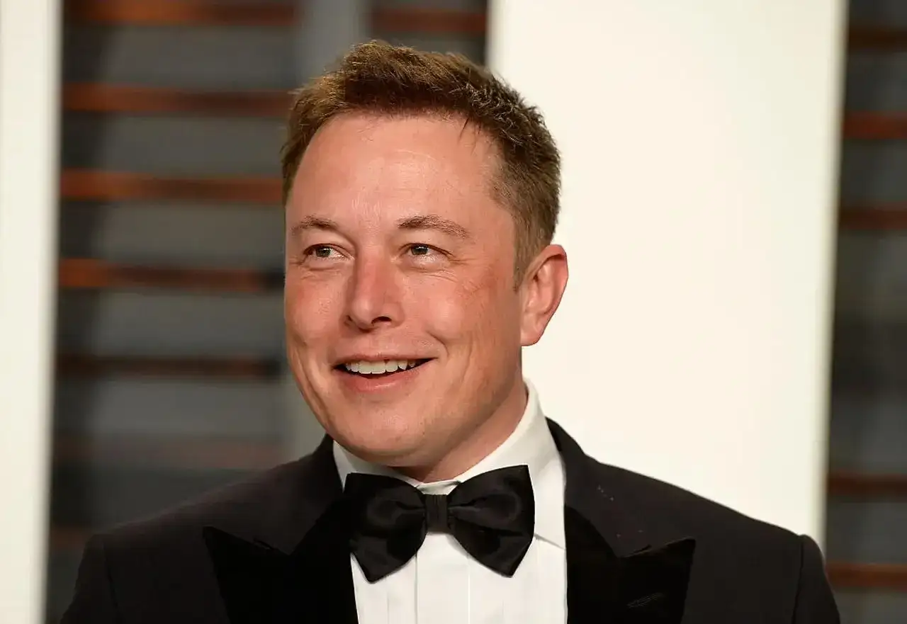 Uśmiechnięty Elon Musk w smokingu z muszką. Jego elon musk data urodzenia to 28 czerwca 1971 roku.