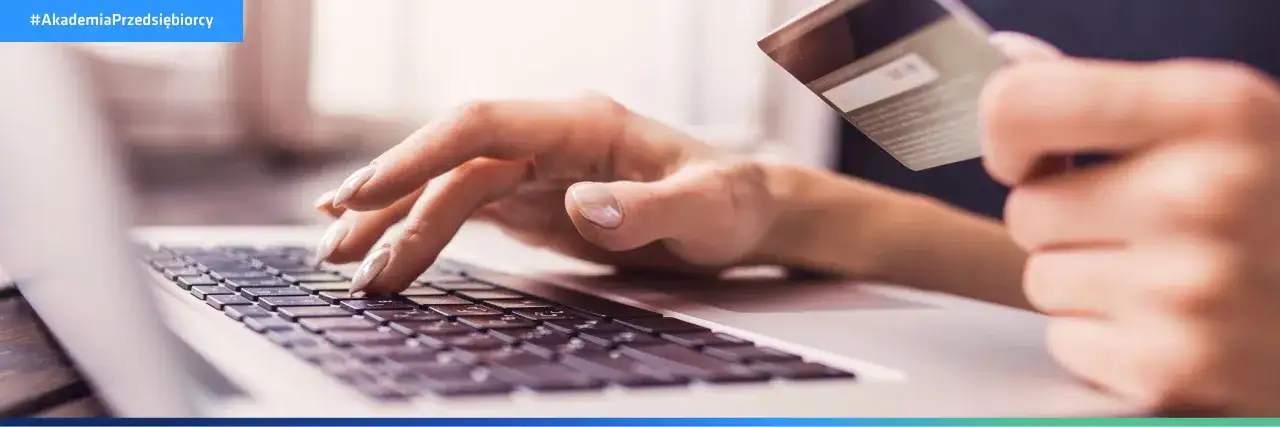 Dłonie wpisujące dane karty płatniczej na klawiaturze laptopa, ilustrujące najpopularniejsze metody płatności online.