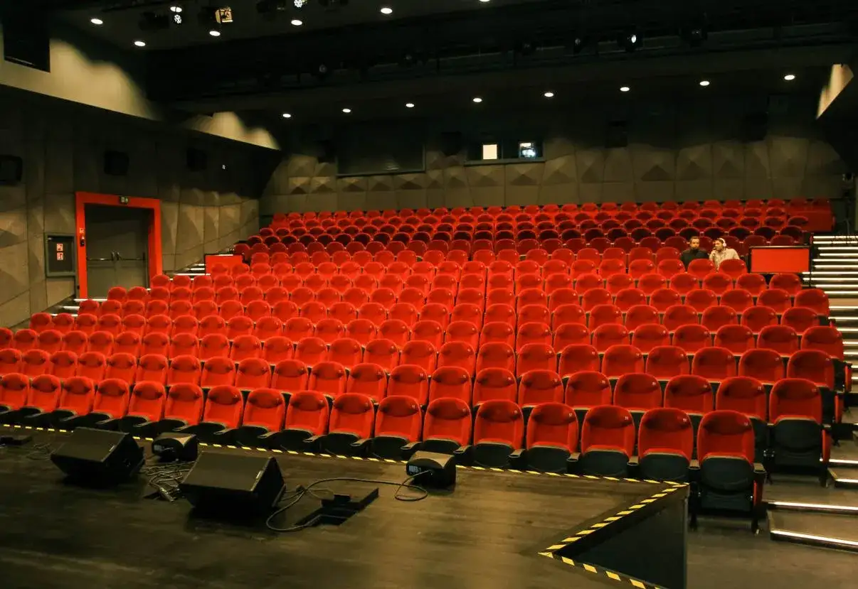 Widok na puste czerwone fotele w sali kinowej lub teatralnej.