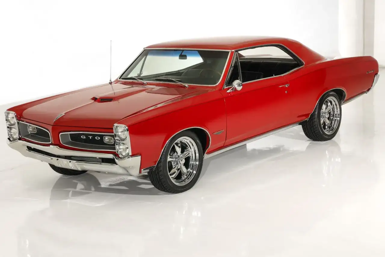 Klasyczny, czerwony Pontiac GTO z chromowanymi felgami, lśniącym lakierem i charakterystyczną atrapą chłodnicy.