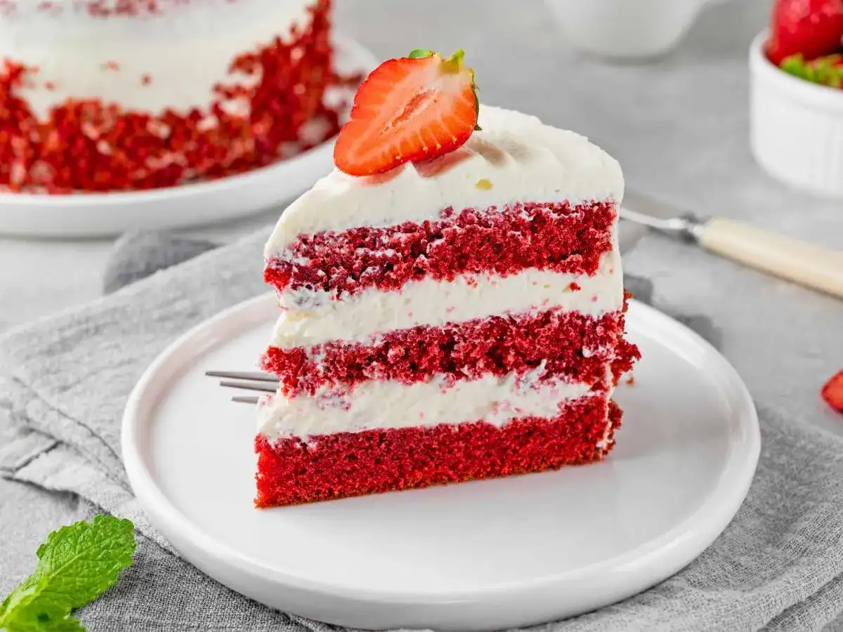Deliciosa tarta red velvet en capas, cubierta con crema y fresa. Un postre irresistible.