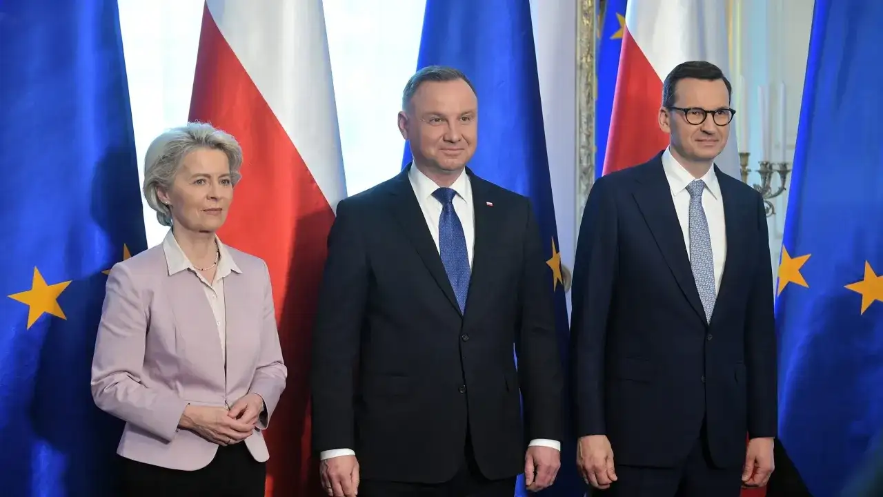 Ursula von der Leyen, Andrzej Duda i Mateusz Morawiecki na tle flag UE i Polski.
