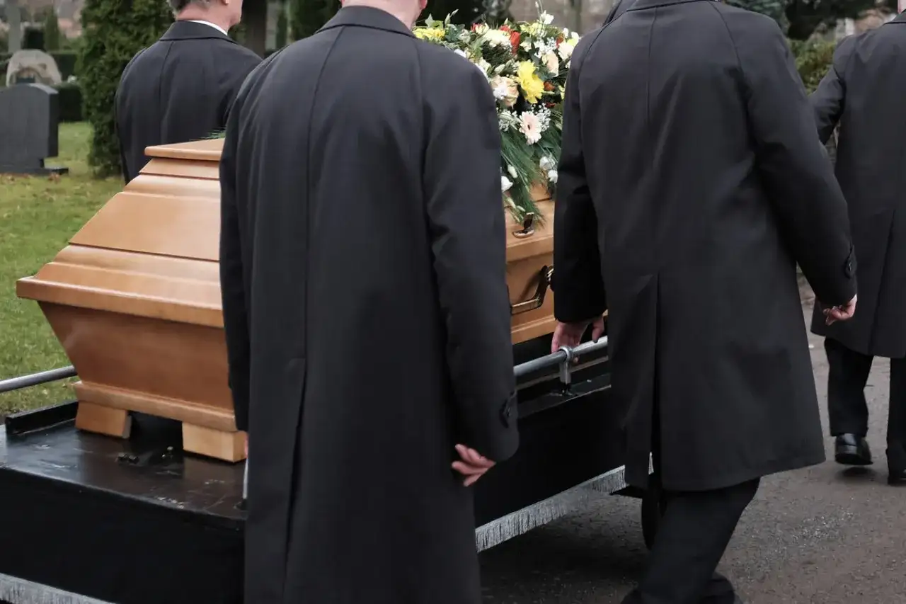 Porteurs en manteaux noirs transportent un cercueil fleuri. La question "peut on être enterré dans son jardin" résonne.