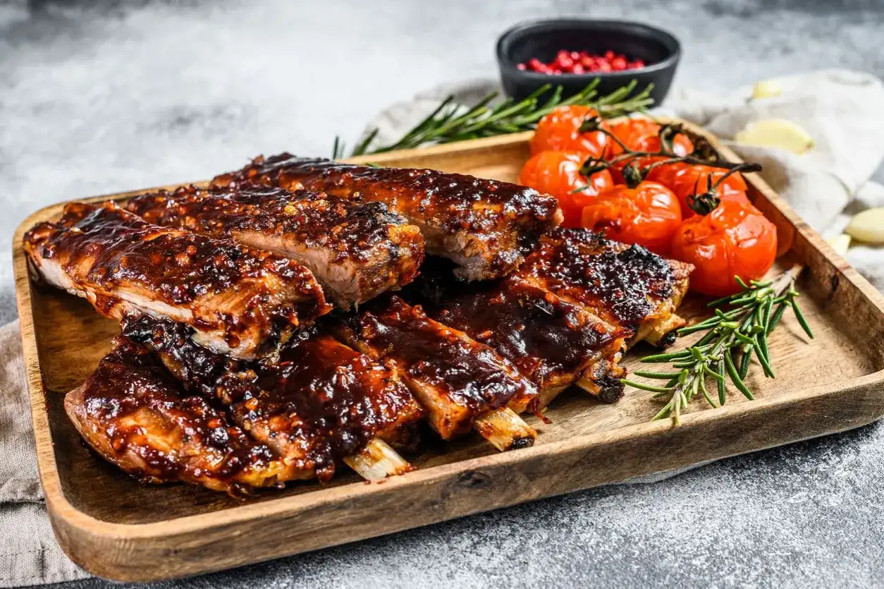 Soczyste żeberka w sosie BBQ, podane z pieczonymi pomidorkami i rozmarynem. Idealne na obiad lub grilla.