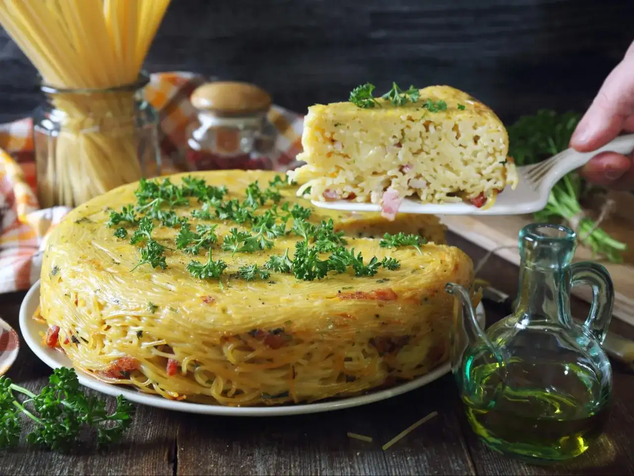 Pyszne spaghetti z piekarnika, zapiekane w formie, z kawałkami boczku i posypane natką pietruszki.