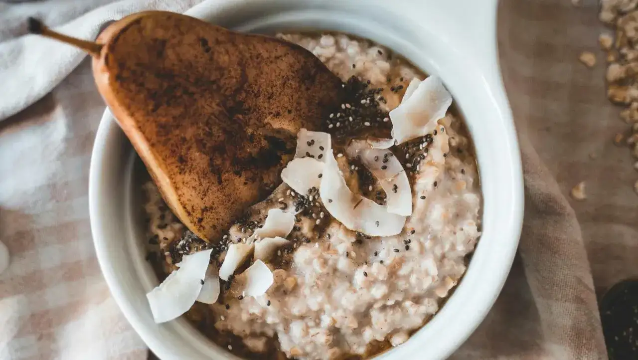 Delicioso porridge de avena con pera, coco rallado y semillas de chía. Un desayuno saludable y nutritivo.