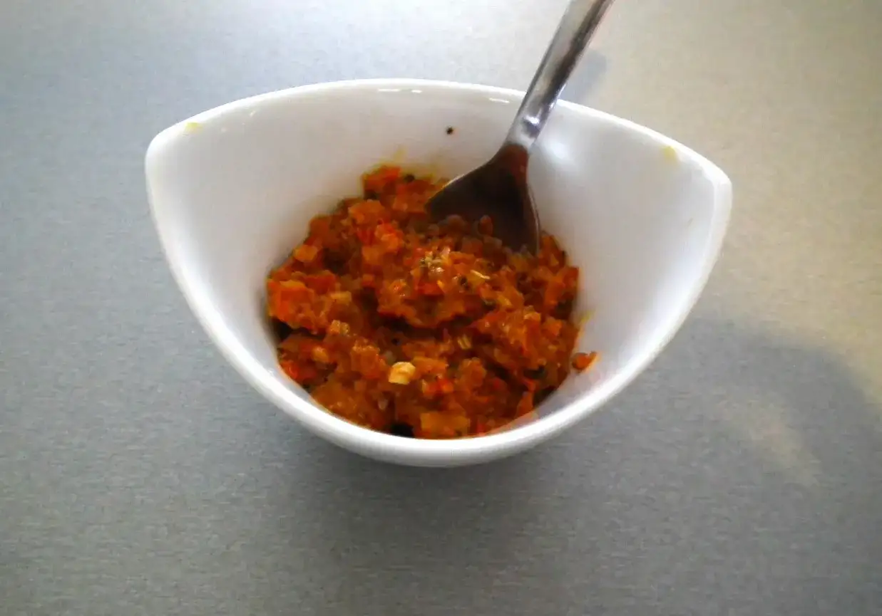 Czerwona pasta curry w białej miseczce z łyżką.