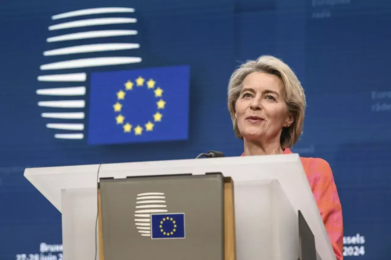 Ursula von der Leyen przemawia na tle flagi UE i logo Komisji Europejskiej.