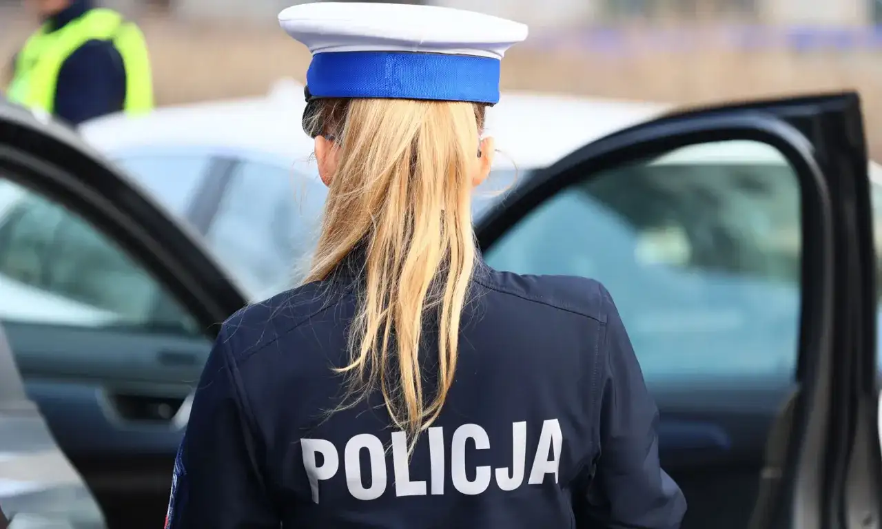 Policjantka w granatowym mundurze z napisem "POLICJA" na plecach, w białej czapce z niebieskim otokiem. Zastanawia się, ile pkt za pasy.