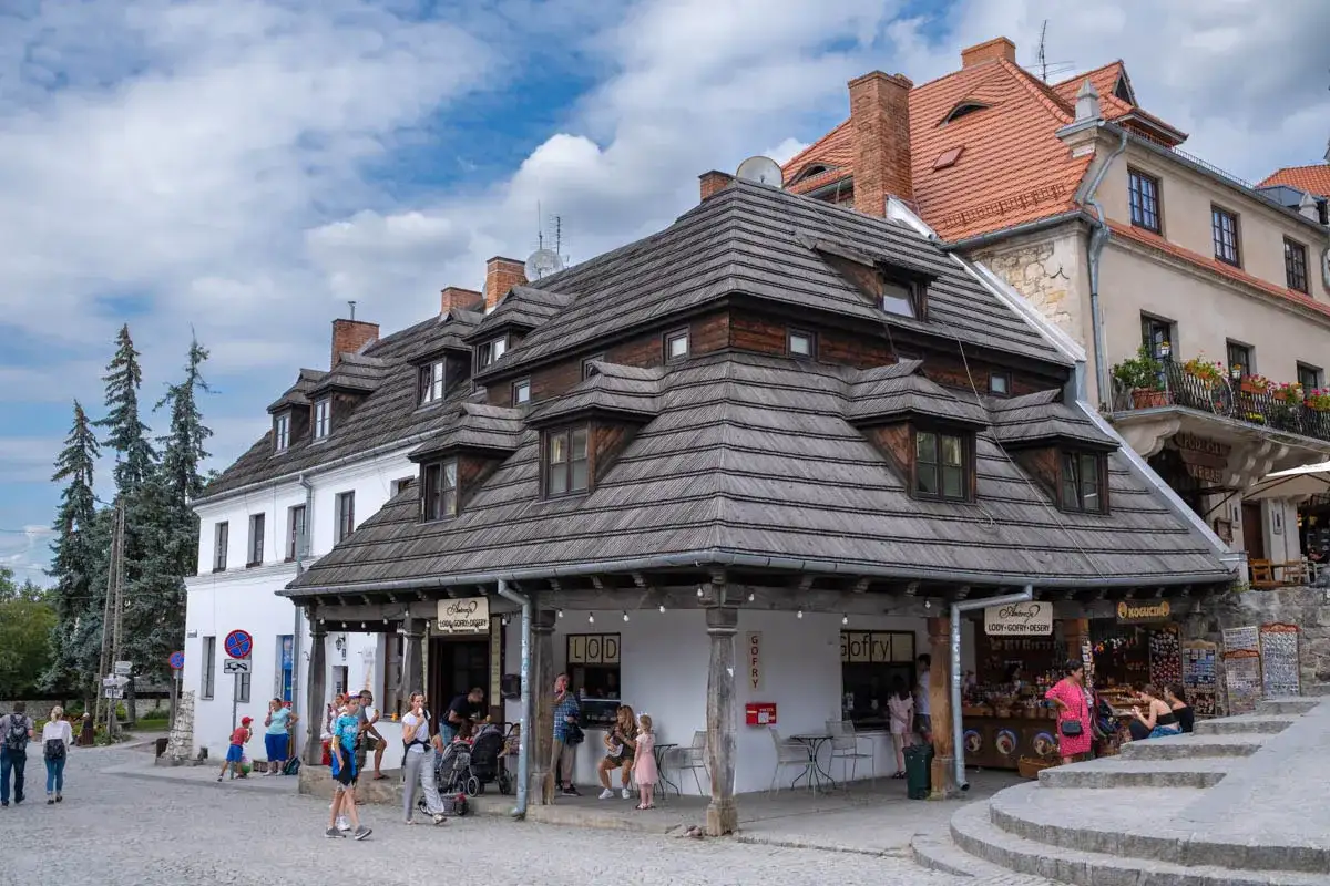 Urokliwe zabytki w Polsce: kamienice o drewnianych dachach i brukowana uliczka z turystami.