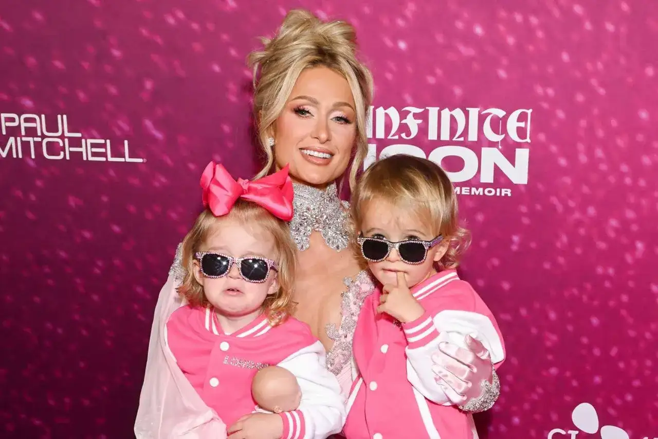Paris Hilton z dwójką uroczych dzieci, obie w różowych kurtkach i okularach przeciwsłonecznych.
