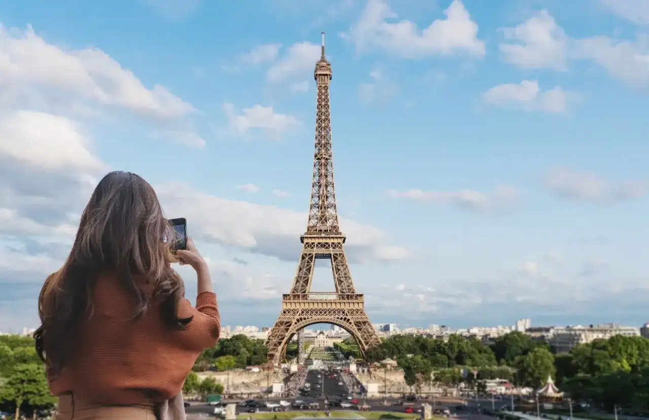 Kobieta robi zdjęcie telefonem ikonicznej wieży Eiffel.