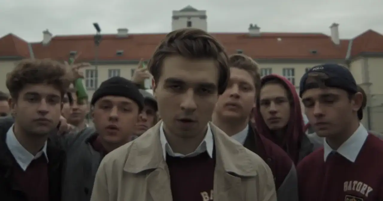 Grupa młodych ludzi, w tym chłopak w beżowej kurtce, zastanawia się, ile lat ma Mata.