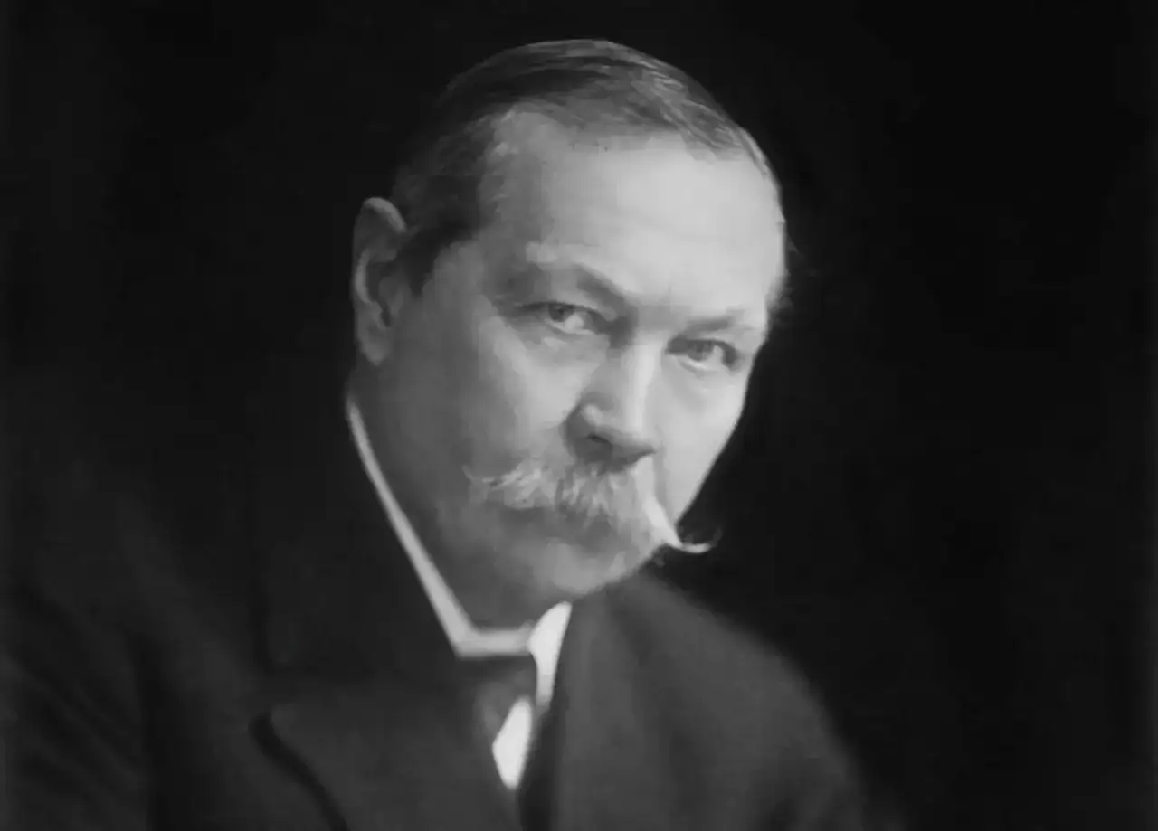 Sir Arthur Conan Doyle, kto jest autorem książek o Sherlocku Holmesie, na czarno-białym portrecie.