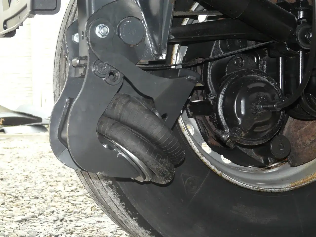 Mechanizm podnoszenia osi BPW z miechem pneumatycznym przy kole ciężarówki.