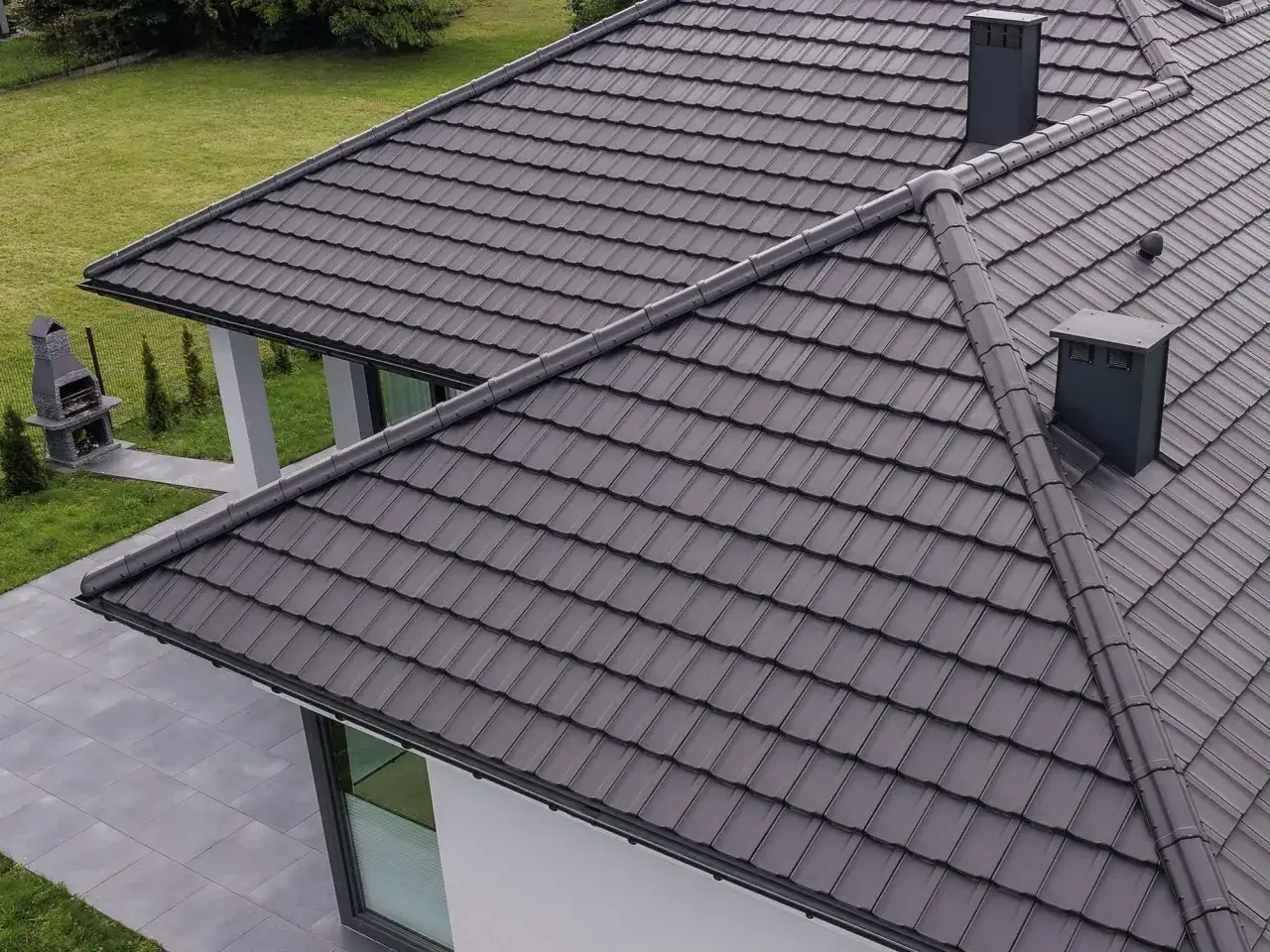 Szary dach z dachówki ceramicznej, z dwoma kominami. Zastanawiasz się, ile waży dachówka ceramiczna?