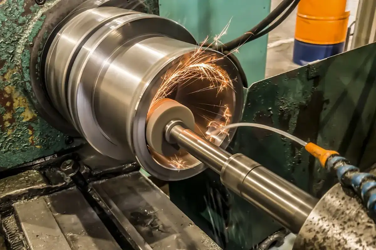 Precyzyjne szlifowanie płaszczyzn cylindrycznego elementu metalowego, iskry sypią się spod ściernicy.