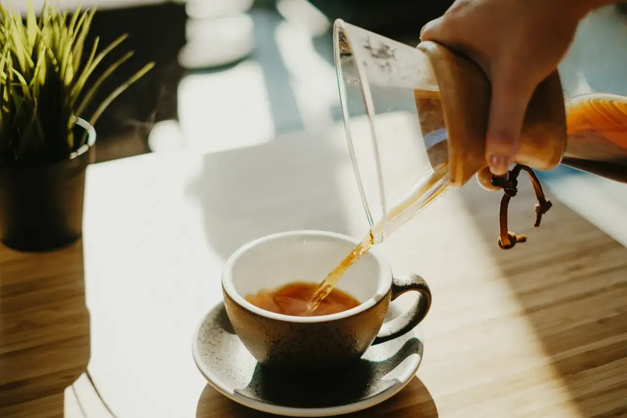 Kawa przelewana z Chemexa do filiżanki, parująca.