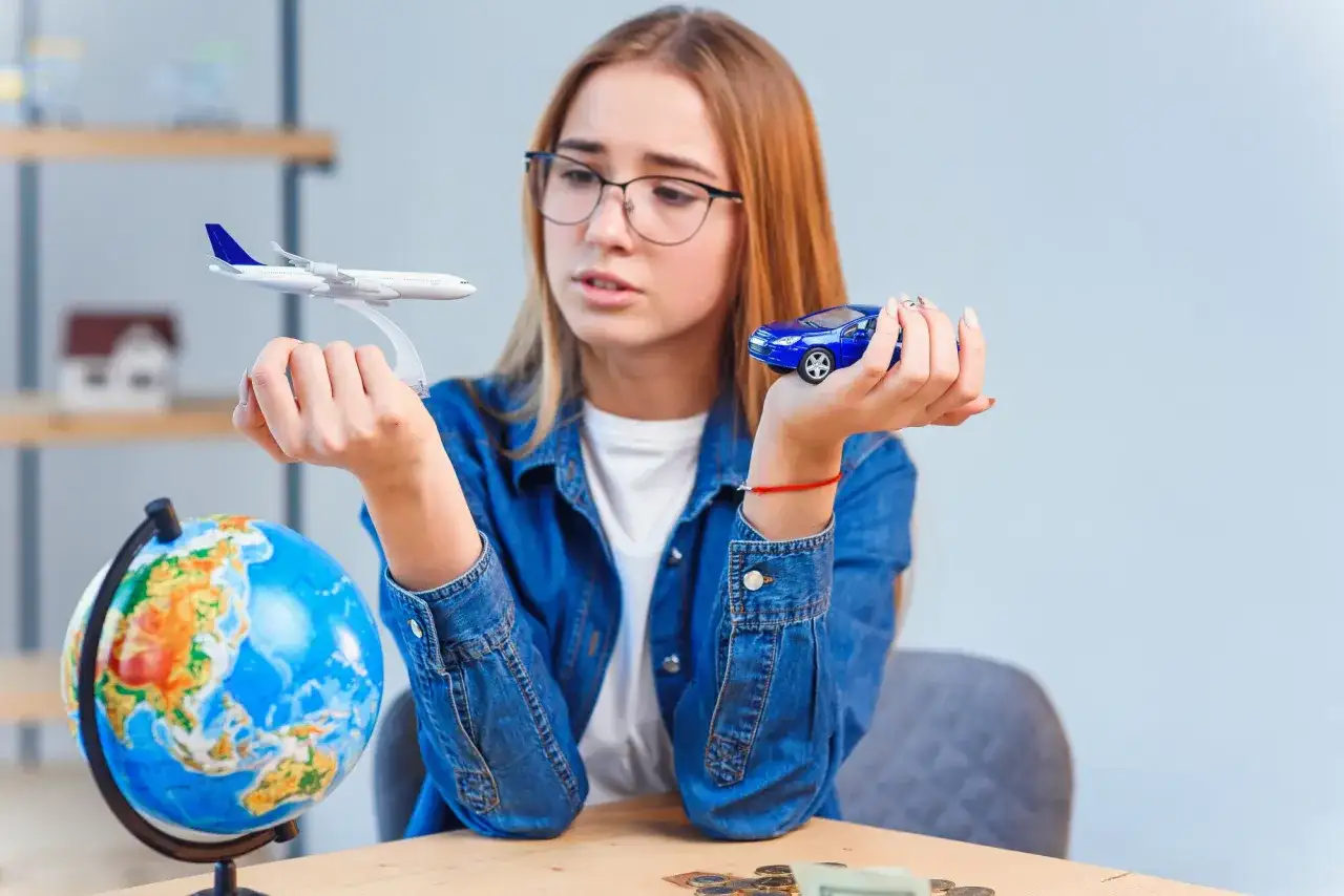 Dziewczyna z globusem i modelami samolotu i auta zastanawia się, jaki kraj wybrać na wakacje. Domena .icu jaki kraj?