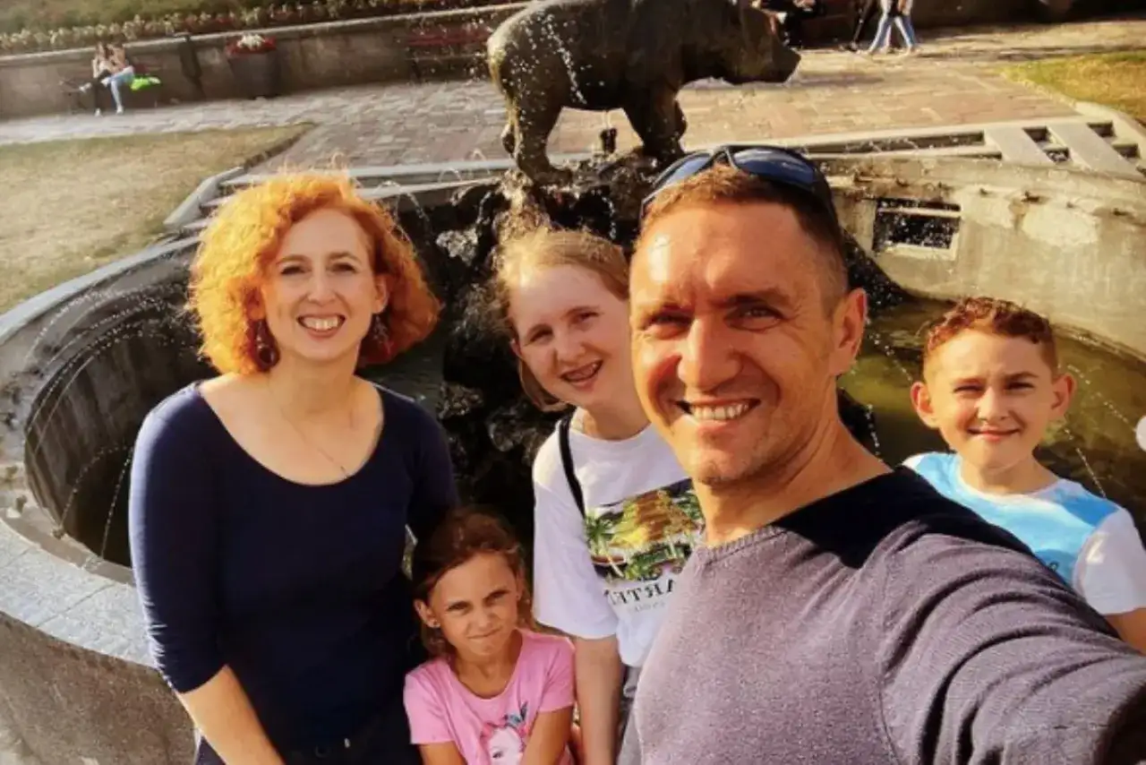 Rodzina pozuje do zdjęcia przy fontannie z rzeźbą niedźwiedzia.