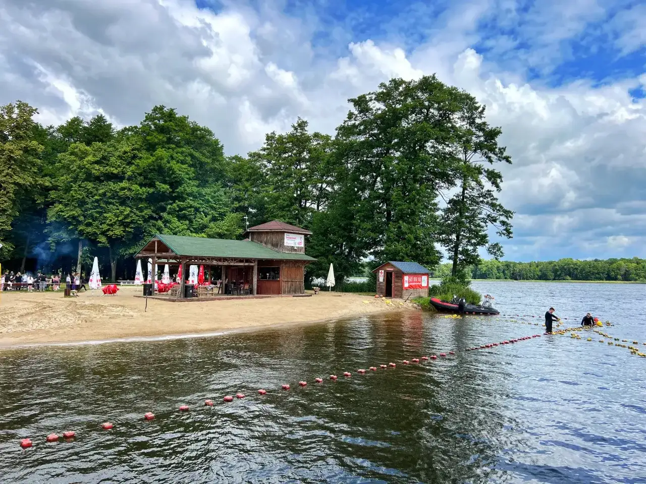 Plaża i jezioro w Szczecinku, z budynkami gastronomicznymi i ludźmi na wodzie. Idealne miejsce na letnie atrakcje.