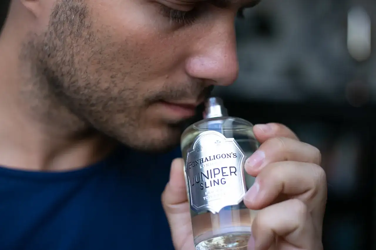 Mężczyzna wącha butelkę wody toaletowej Penhaligon's Juniper Sling.