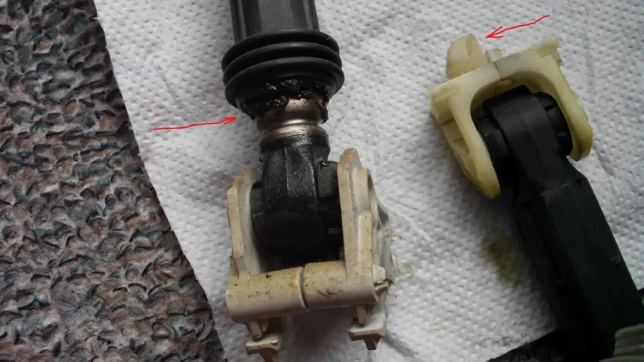 Zużyty amortyzator pralki Whirlpool z widocznymi uszkodzeniami i smarem.