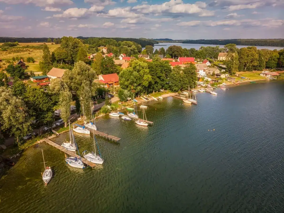 Malowniczy widok na przystań żaglową w Drawskim Parku Krajobrazowym. Woda, łodzie i zielone otoczenie tworzą sielski obraz.