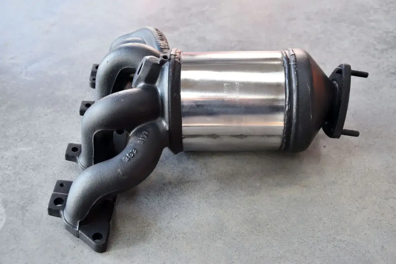 Nowy katalizator samochodowy z czarnym kolektorem i metalową obudową.