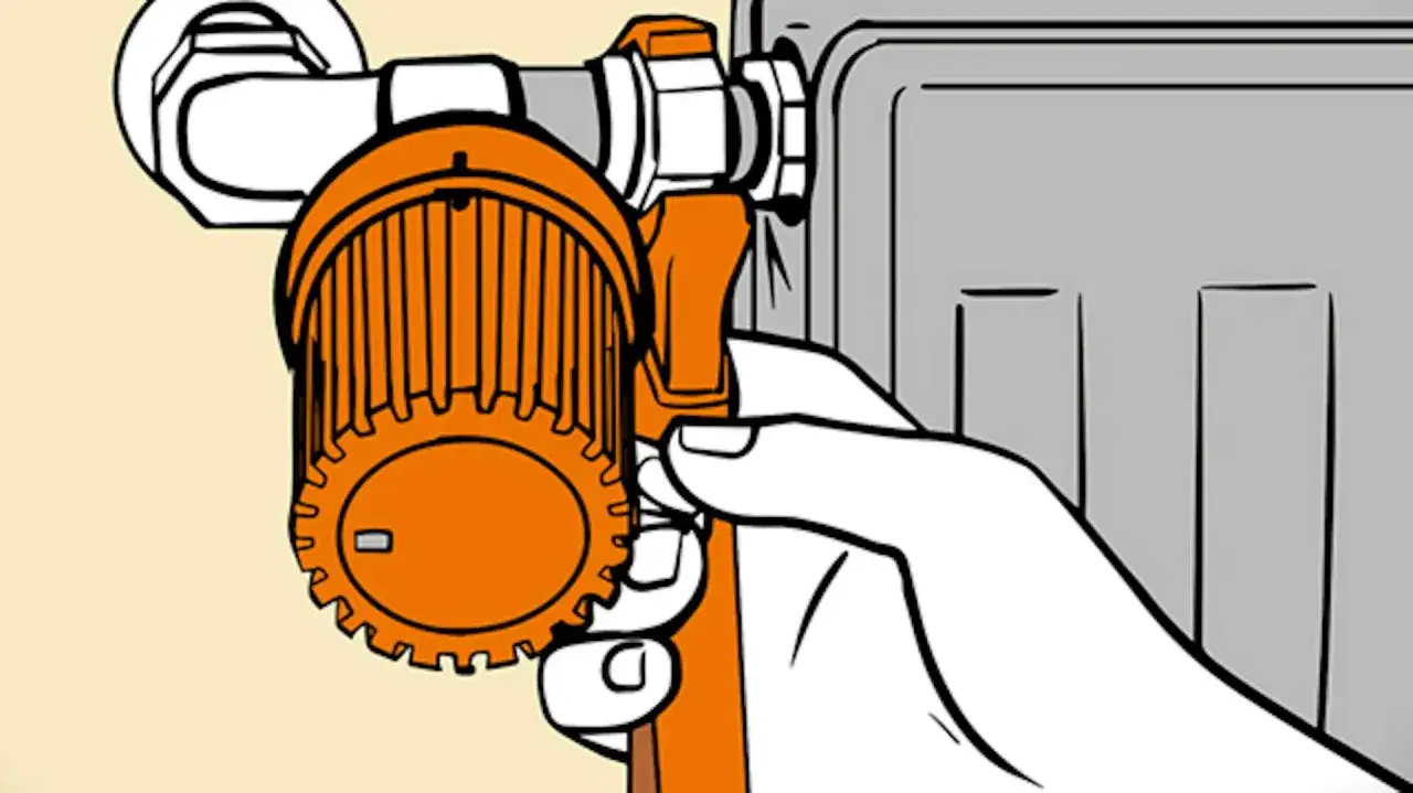 Dłoń chwyta termostat grzejnika, pokazując, jak odkręcić grzejnik, by wyregulować temperaturę.