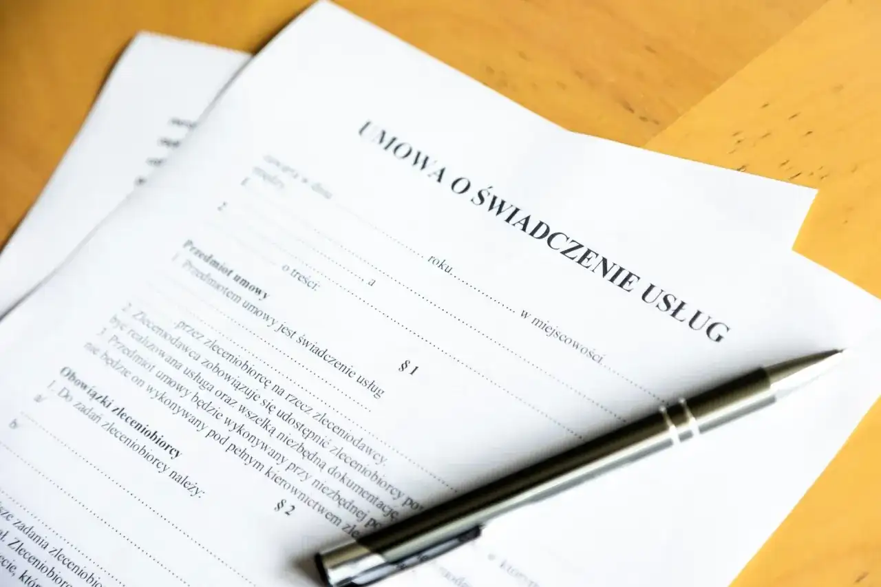 Umowa o świadczenie usług. Czy świadczenie integracyjne wlicza się do stażu pracy? Długopis leży na dokumencie.