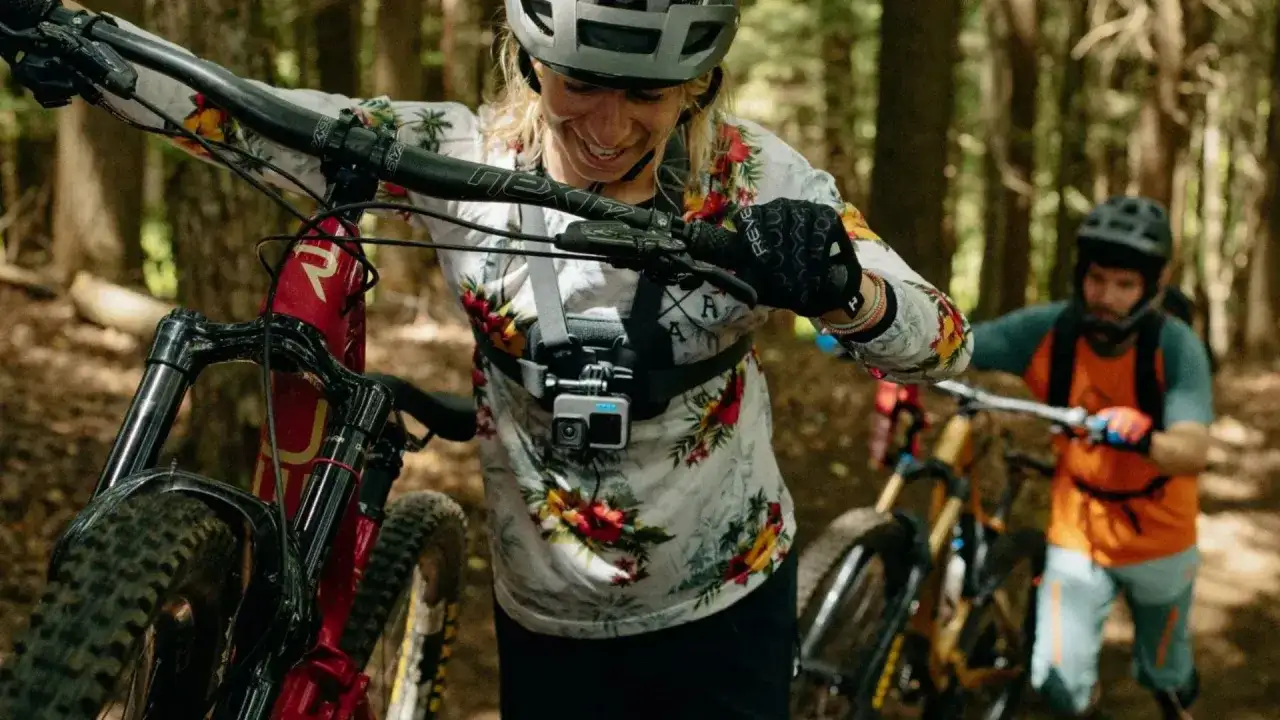 Kamera sportowa na kask rejestruje emocje z górskiej trasy. Kobieta z rowerem w lesie, gotowa na przygodę.