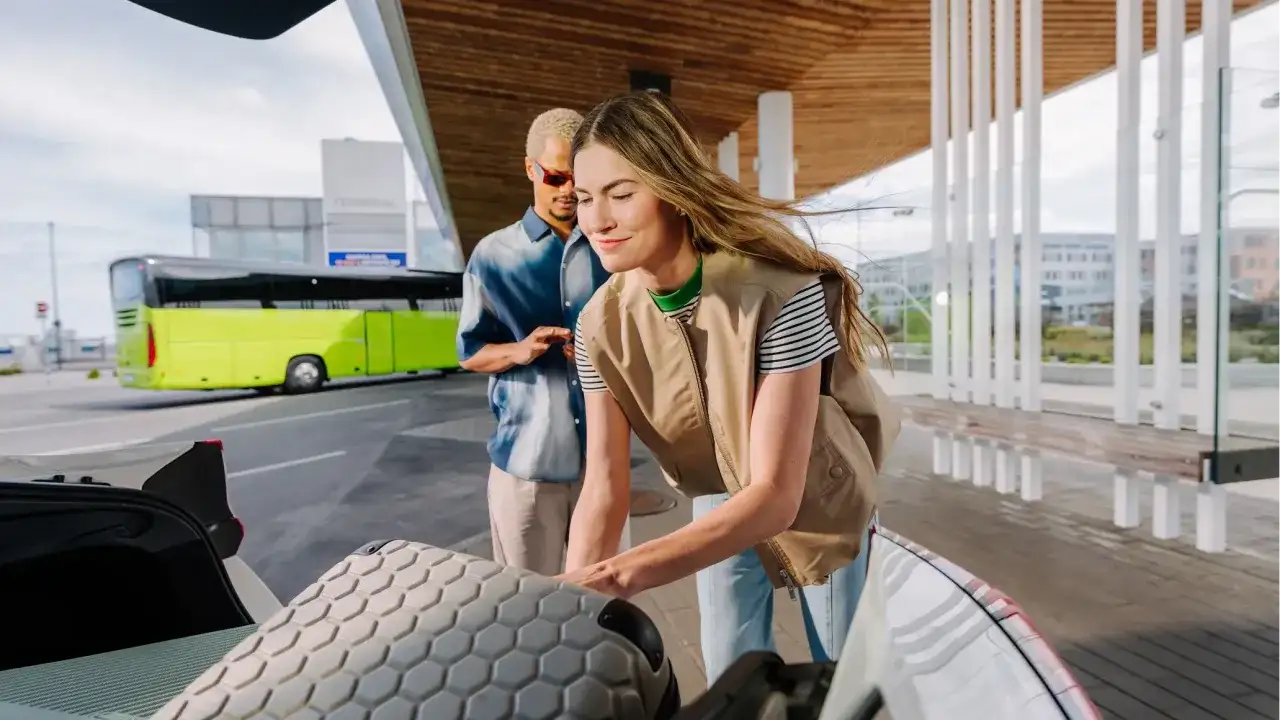 Para dojechać do Złotych Tarasów, wsiądź do zielonego autobusu na terminalu. Para pakuje bagaże do bagażnika.