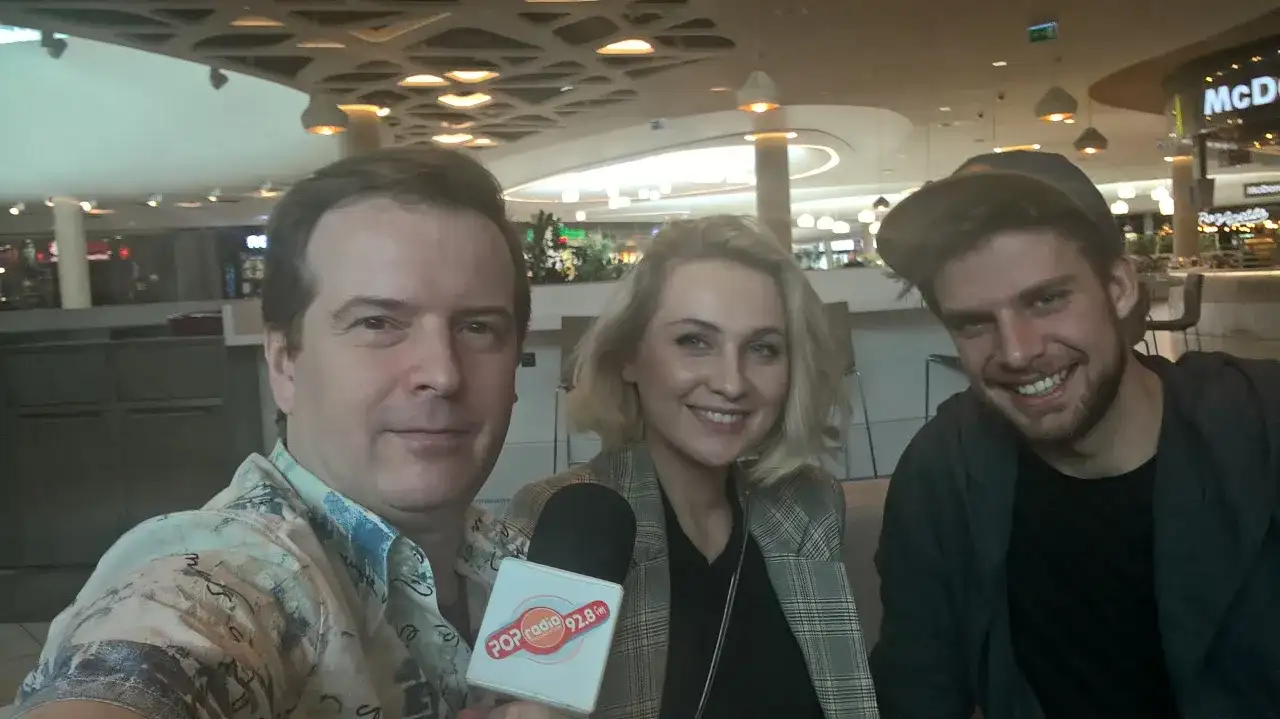 Trzy osoby pozujące do zdjęcia z mikrofonem Popradio.