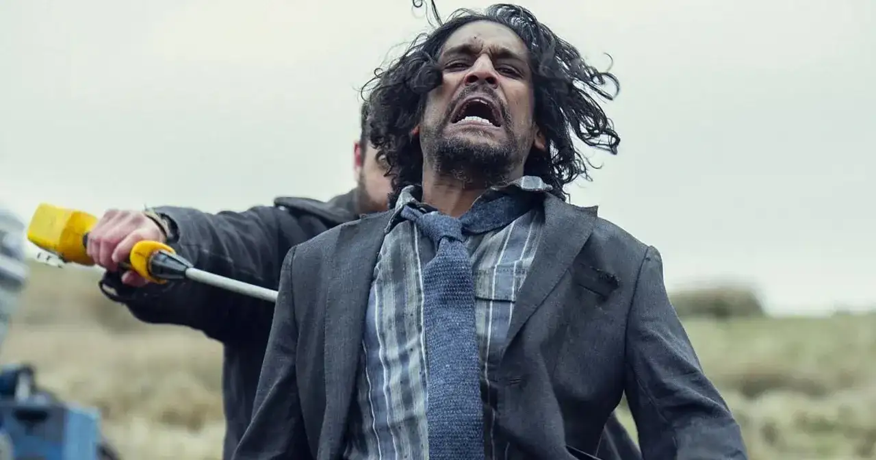 Mężczyzna w garniturze krzyczy, gdy ktoś trzyma go za rękę z żółtym przedmiotem. Scena z serialu "Tęsknię za tobą".