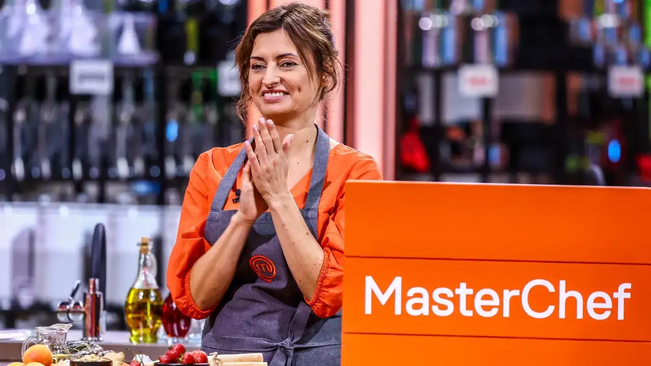 Barbara Tomkowiak w fartuchu MasterChef, z dłońmi złożonymi w geście radości.