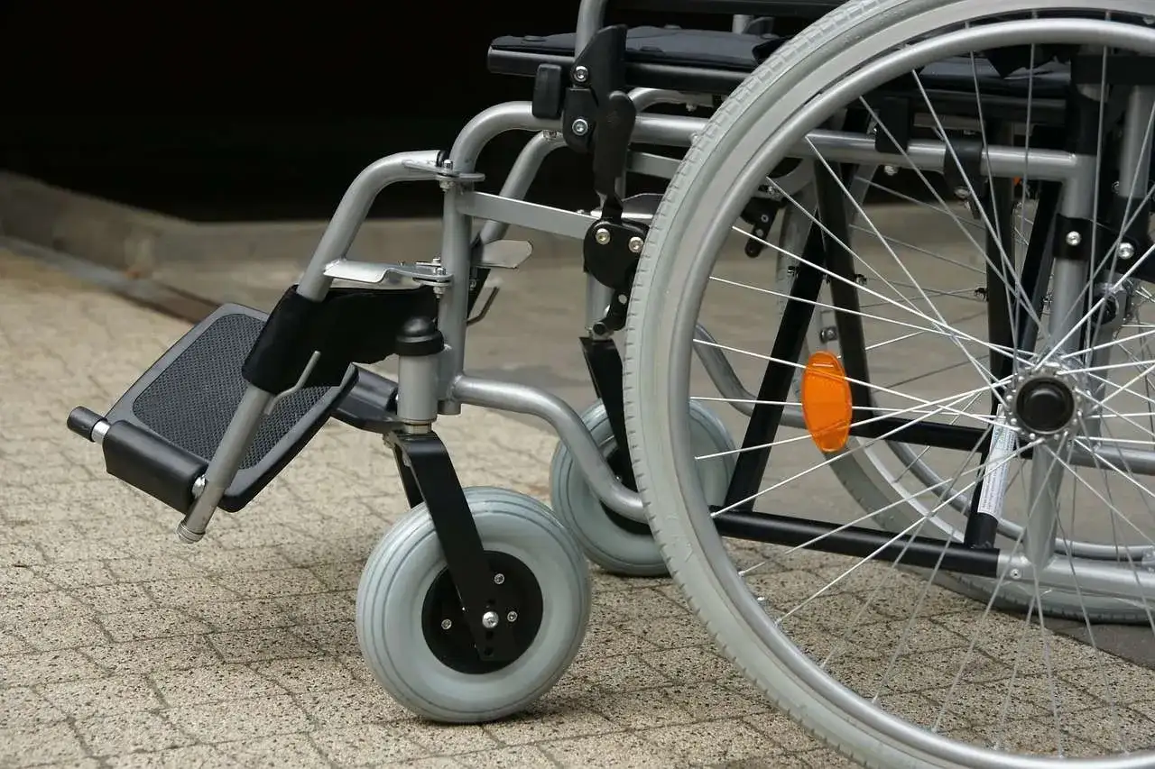 Zbliżenie na wózek inwalidzki z widocznymi kołami i podnóżkiem.