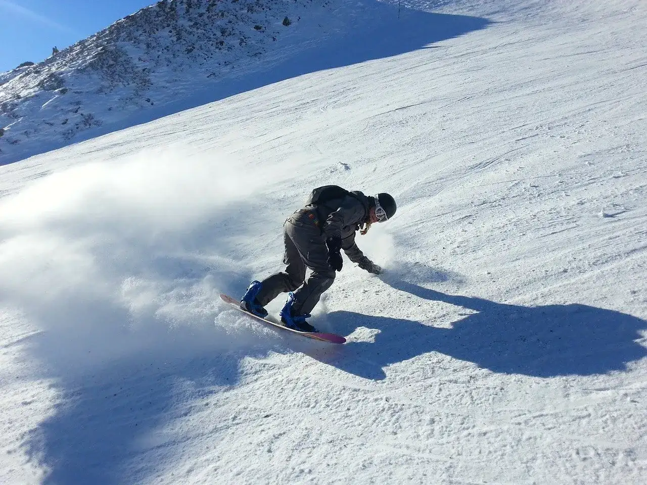 Snowboardzista w akcji na stoku, tworząc obłok śniegu. Idealne **deski do freeride** pozwalają na takie ewolucje.