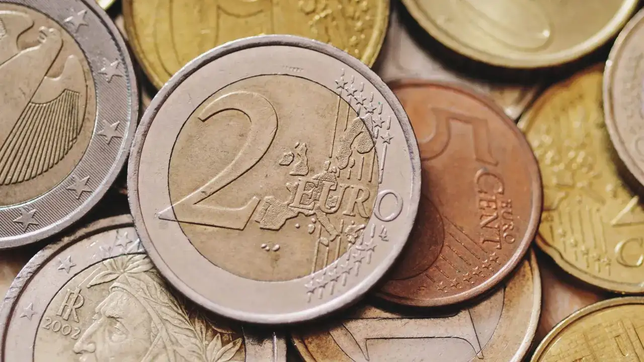 Zbliżenie na stos monet euro, w tym monety 2 euro i 5 centów.