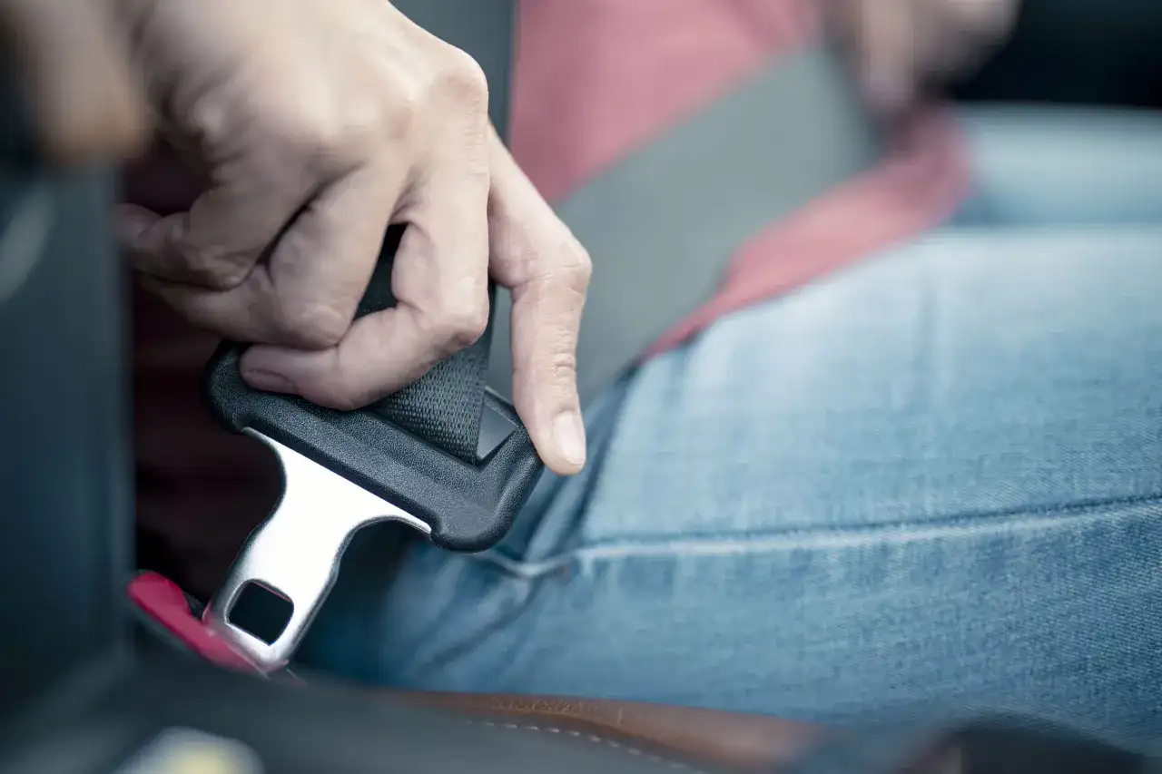 Dłoń zapina pas bezpieczeństwa w samochodzie.