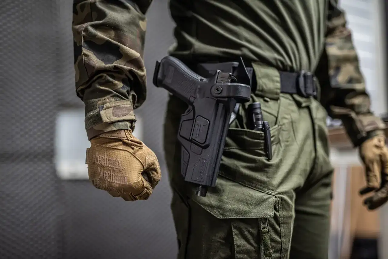 Czy myśliwy może nosić broń w miejscu publicznym? Na zdjęciu widać mężczyznę w mundurze z kaburą na pistolet.