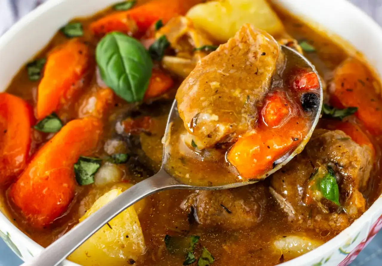 Gulasz z baraniny z marchewką i ziemniakami na łyżce.