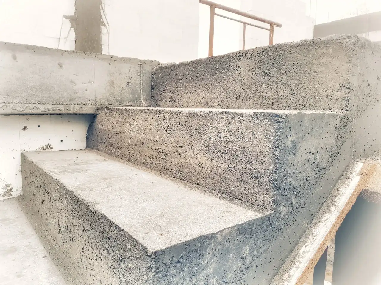 Betonowe schody w trakcie budowy. Widać surowe stopnie i ściany, gotowe do wykończenia. To pierwszy etap, jak wylać schody.