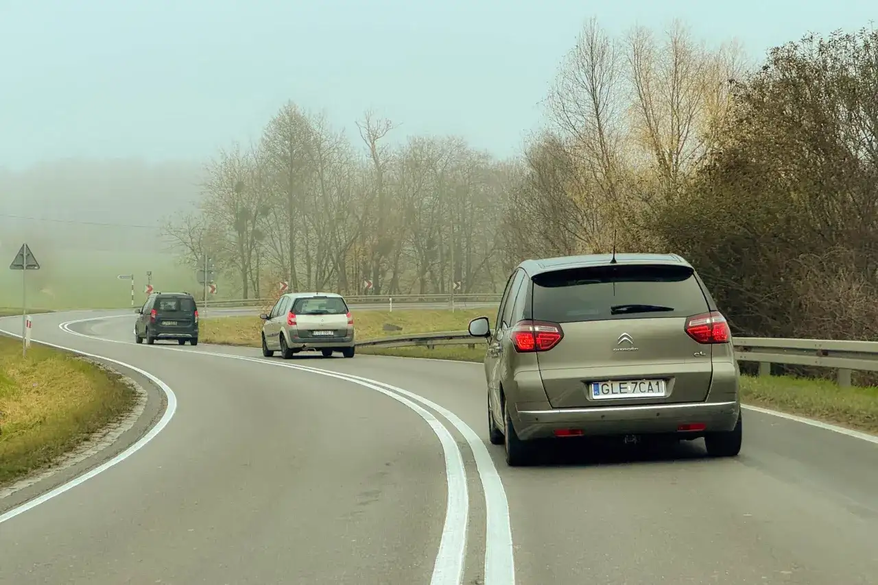 Samochody na mglistej drodze. Myśląc o tym, jak wyrobić prawo jazdy, warto pamiętać o ostrożności na zakrętach.
