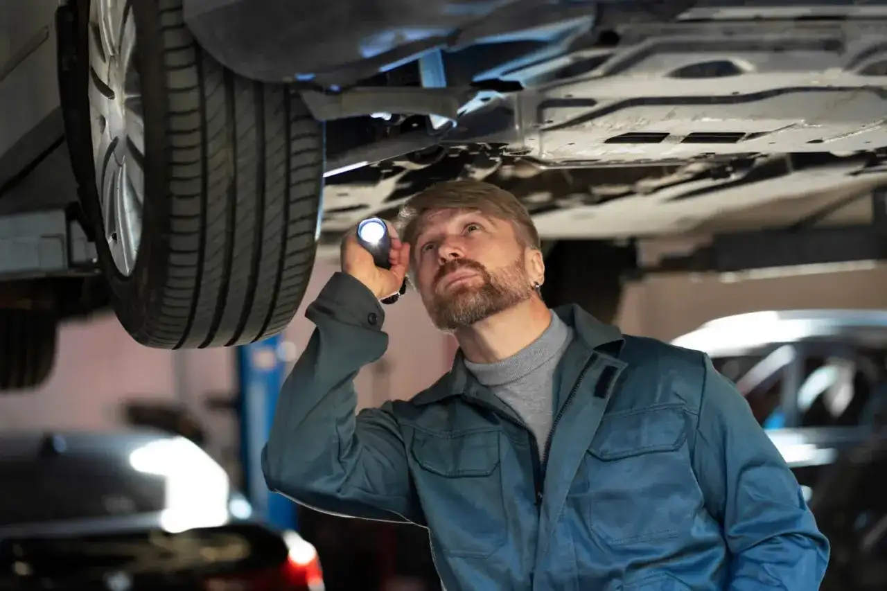 Mechanik bada podwozie auta, szukając uszkodzone jarzmo zacisku objawy.
