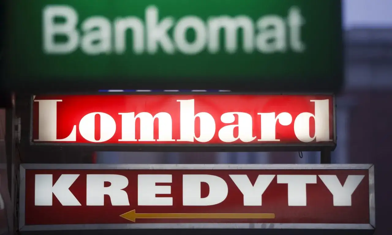 Jasny szyld "Lombard" nad napisem "KREDYTY" i niewyraźnym "Bankomat". Chcesz wiedzieć, jak otworzyć lombard?